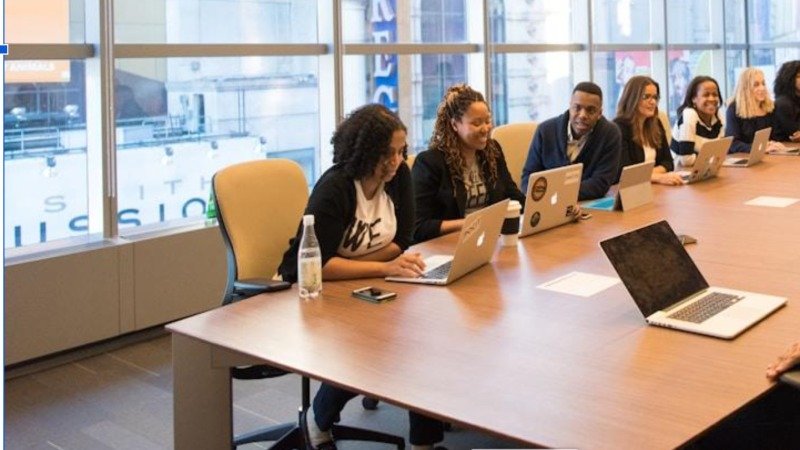 Alt text: Team members collaborating in a meeting room, discussing the principles of tech knowledge management and its importance in the tech industry 